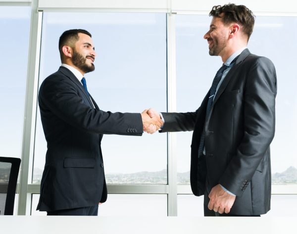 Building collaborative teamwork. Handsome businessman and business executive getting to know each other while shaking hands during a work meeting